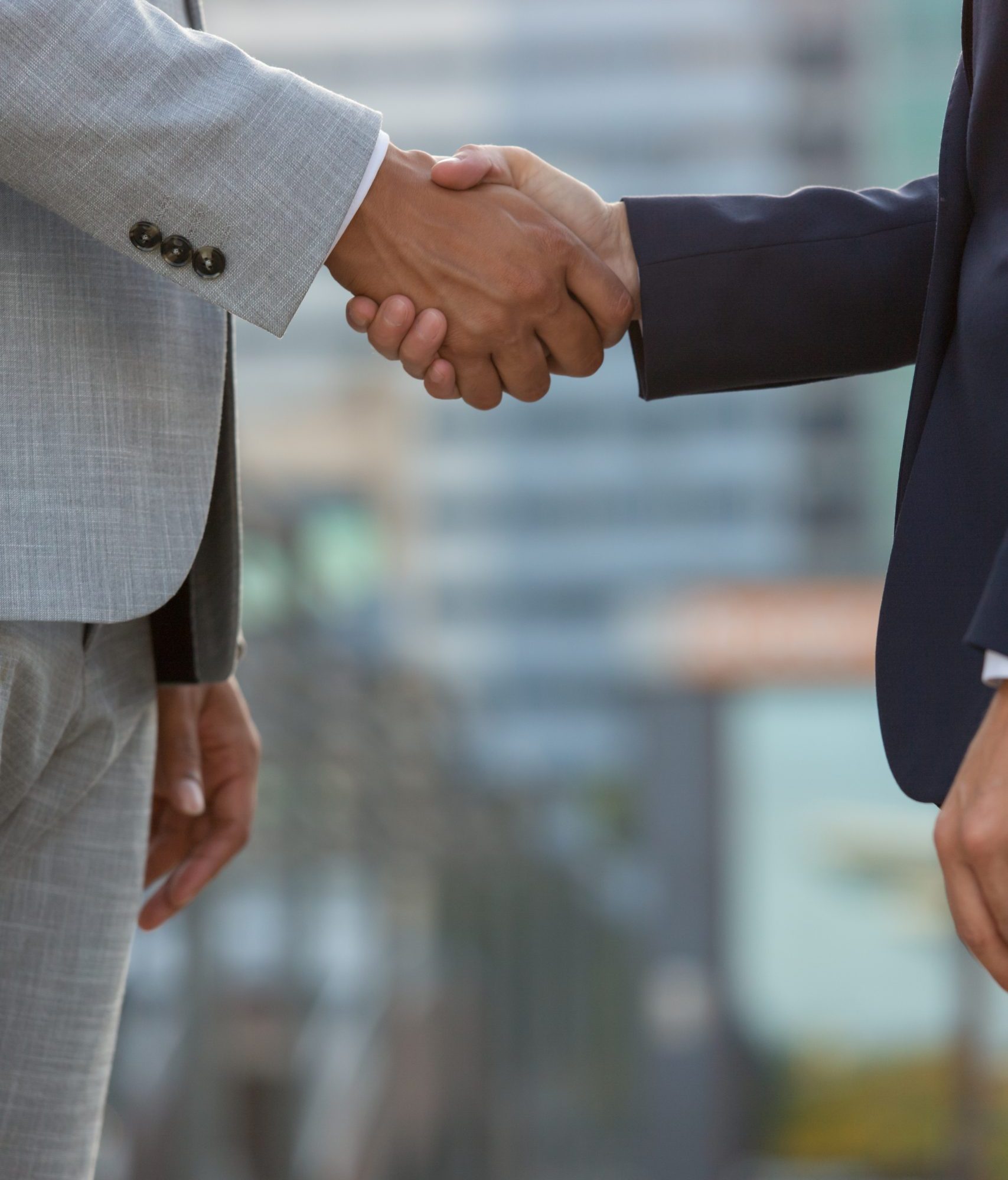Businesspeople standing in city street and shaking hands Businesspeople standing in city street and shaking hands. Business man and woman in office suits meeting outside. Successful partnership concept